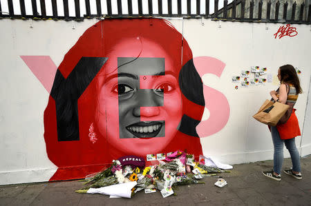A woman looks at a new mural of Savita Halappanavar with flowers placed beneath it put up on the day of the Abortion Referendum on liberalising abortion laws in Dublin, Ireland May 25, 2018. REUTERS/Clodagh Kilcoyne