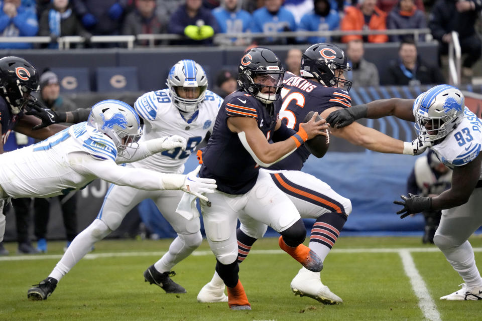 Chicago Bears quarterback Justin Fields scrambles away from Detroit Lions defensive end Aidan Hutchinson, left, and defensive end Josh Paschal during the first half of an NFL football game Sunday, Dec. 10, 2023, in Chicago. (AP Photo/Nam Y. Huh)