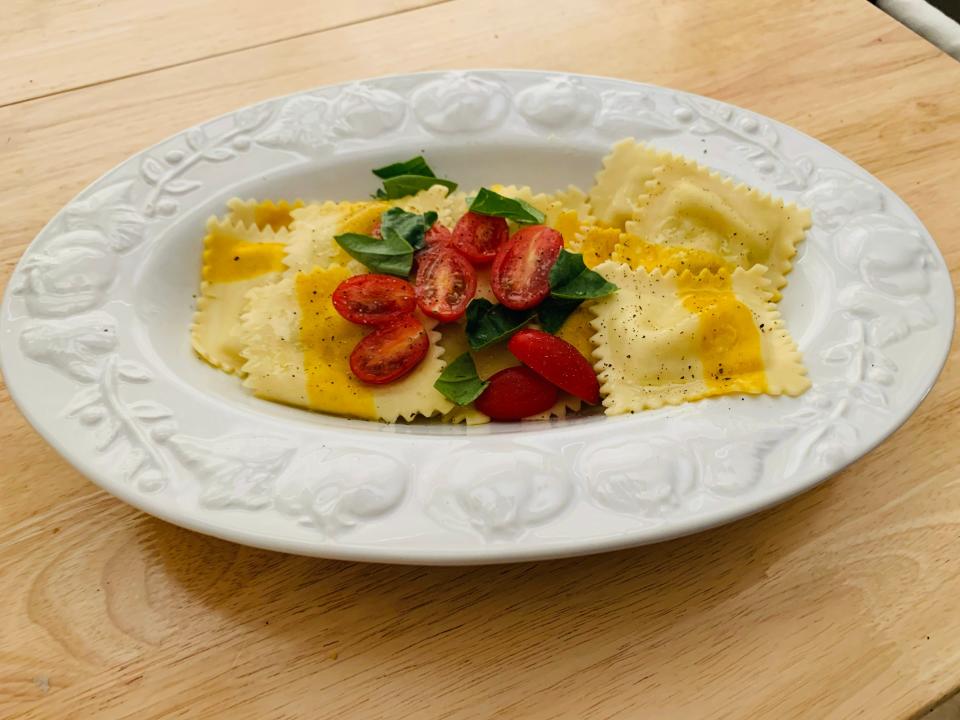 Trader Joe's sweet corn and burrata ravioli served on a white plate and garnished with cherry tomatoes and basil