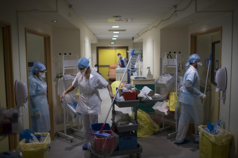 Medical workers wearing protective layers of plastic prepare to clean rooms in the hallway of a makeshift ICU at the La Timone hospital in Marseille, southern France, Thursday, Nov. 12, 2020. (AP Photo/Daniel Cole)