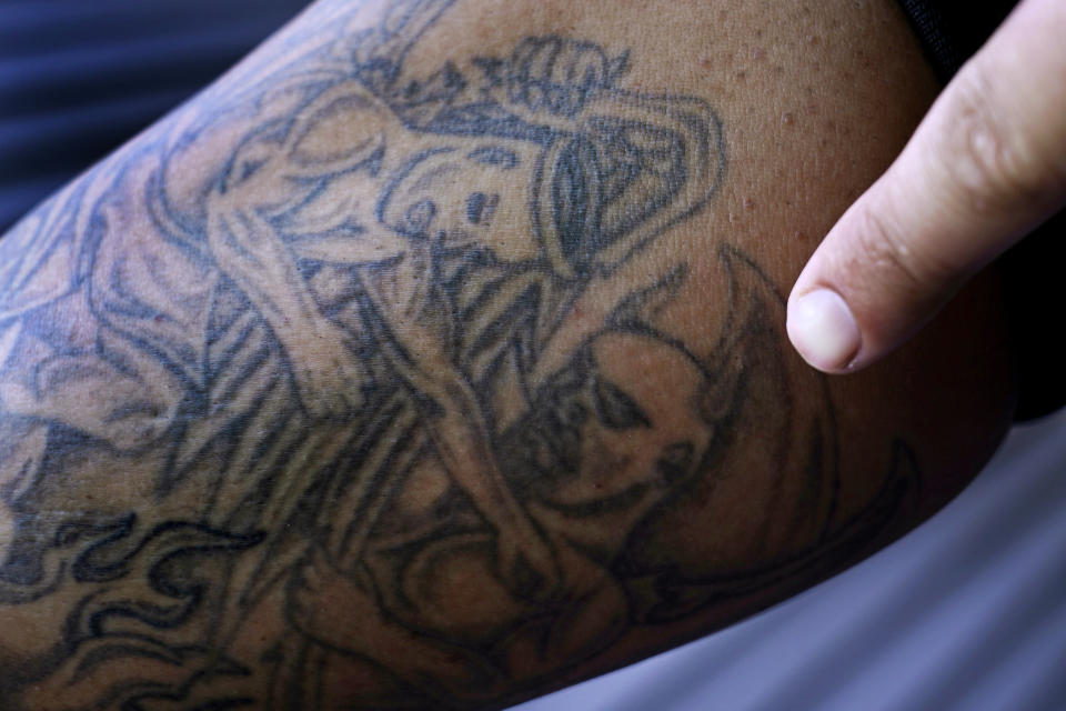 Mike Gilpatrick, who as a teenager was incarcerated at the Youth Development Center, points out one of his tattoos, of an angel battling a demon that was inked in prison, at his home, Wednesday, Sept. 8, 2021, in Nashua, N.H. Gilpatrick, 38, filed a lawsuit Monday Sept. 13, alleging he was physically and sexually abused at the former YDC in Manchester, which has been the target of a criminal investigation since 2019 and is slated to close in 2023. (AP Photo/Charles Krupa)