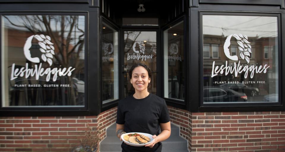 LesbiVeggies owner Brennah Lambert holds a plate of eggplant parmesan and spaghetti as she stands in front of her plant-based and gluten-free Audubon cafe.