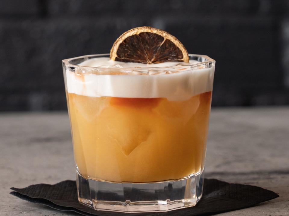 Amaretto-Sour-Cocktail mit einer getrockneten Orangenscheibe auf einer Cocktailserviette