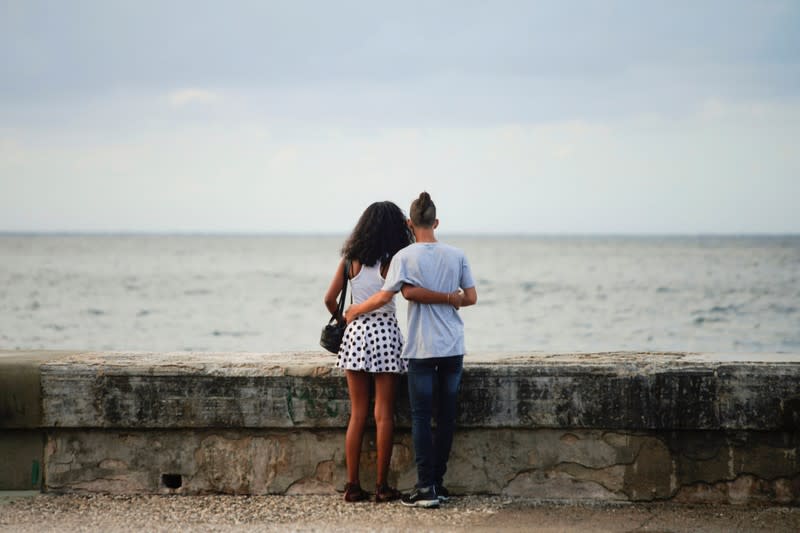 A couple stand at the seafront in Havana