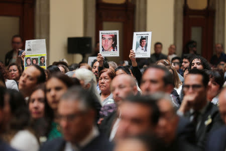 Relatives of some of the many people registered as disappeared show pictures as Mexico's President Andres Manuel Lopez Obrador (not pictured) gives his address at the National Palace in Mexico City, Mexico March 24, 2019. Press Office Andres Manuel Lopez Obrador/Handout via REUTERS
