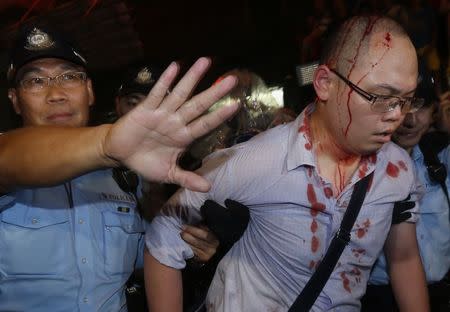 A policeman helps an injured pro-democracy protester to leave after he was beaten by a group of anti-Occupy Central protesters at Hong Kong's Mongkok district in this October 3, 2014 file photo. REUTERS/Bobby Yip/Files