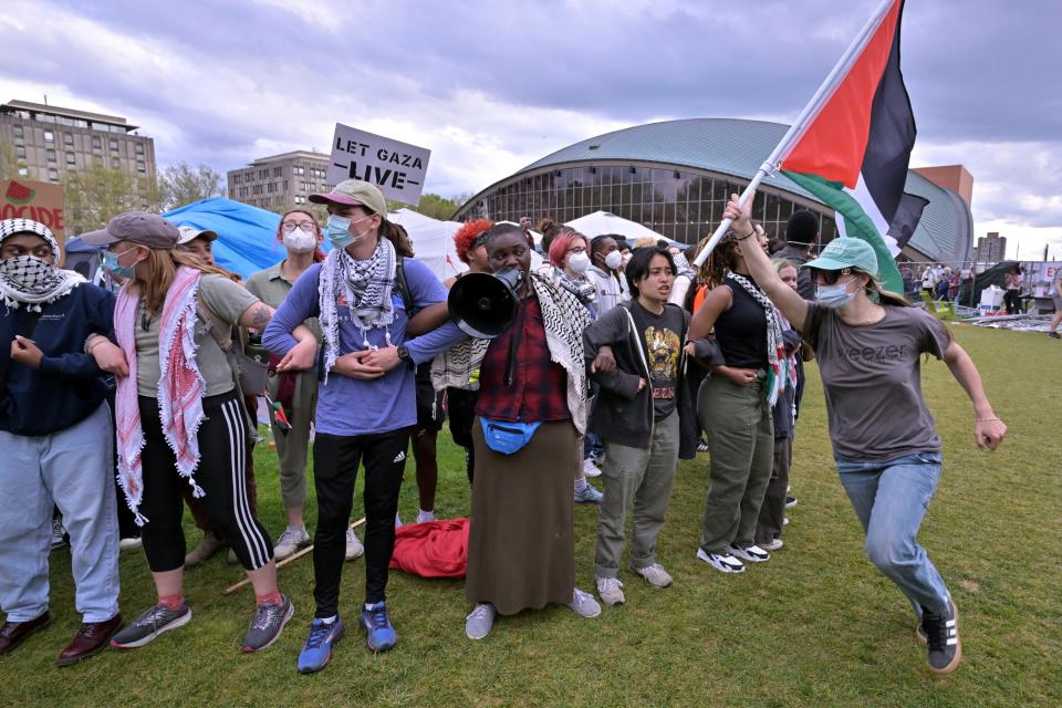 A demonstrator carries a Palestinian flag beside a line of demonstrators Monday, May 6, 2024, in at MIT in Cambridge, Mass. after several hundred demonstrators crossed torn down barricades and joined pro-Palestinian demonstrators that been given a deadline to leave the encampment. (AP Photo/Josh Reynolds)