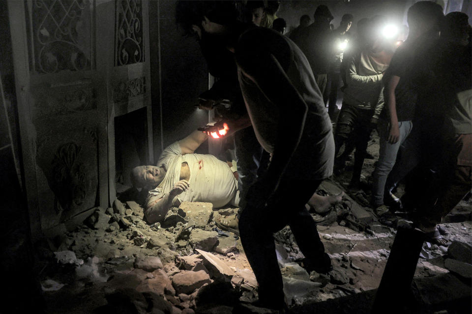 People approach with flashlights an injured person lying amidst rubble on the ground at the site of a building that was hit by Israeli bombardment in Rafah, southern Gaza Strip, on May 7, 2024 amid the ongoing conflict in the Palestinian territory.. <span class="copyright">AFP/Getty Images</span>