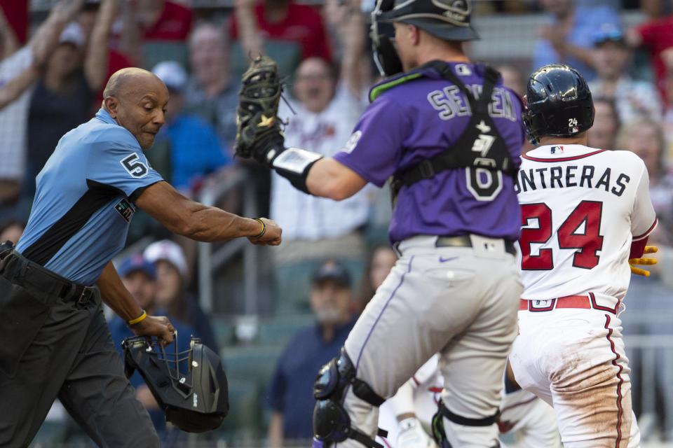 Umpire CB Bucknor left, calls Atlanta Braves William Contreras right, out after the tag made by Colorado Rockies catcher Brian Serven, center, in the first inning of a baseball game Wednesday, Aug. 31, 2022, in Atlanta. (AP Photo/Hakim Wright Sr.)