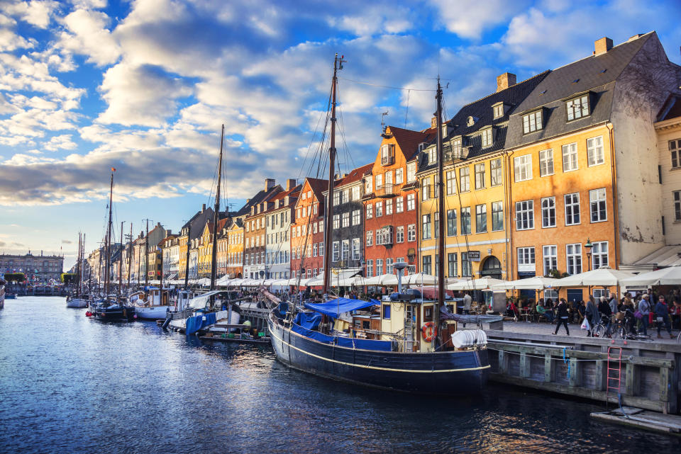 A colorful row of houses along a water bank lined with sailboats.