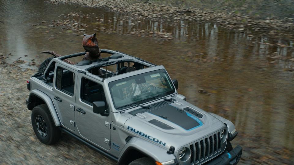 A dinosaur rides in the back of a Jeep Wrangler 4xe plug-in hybrid electric vehicle in a new ad that ties in with the opening this month of "Jurassic World Dominion."