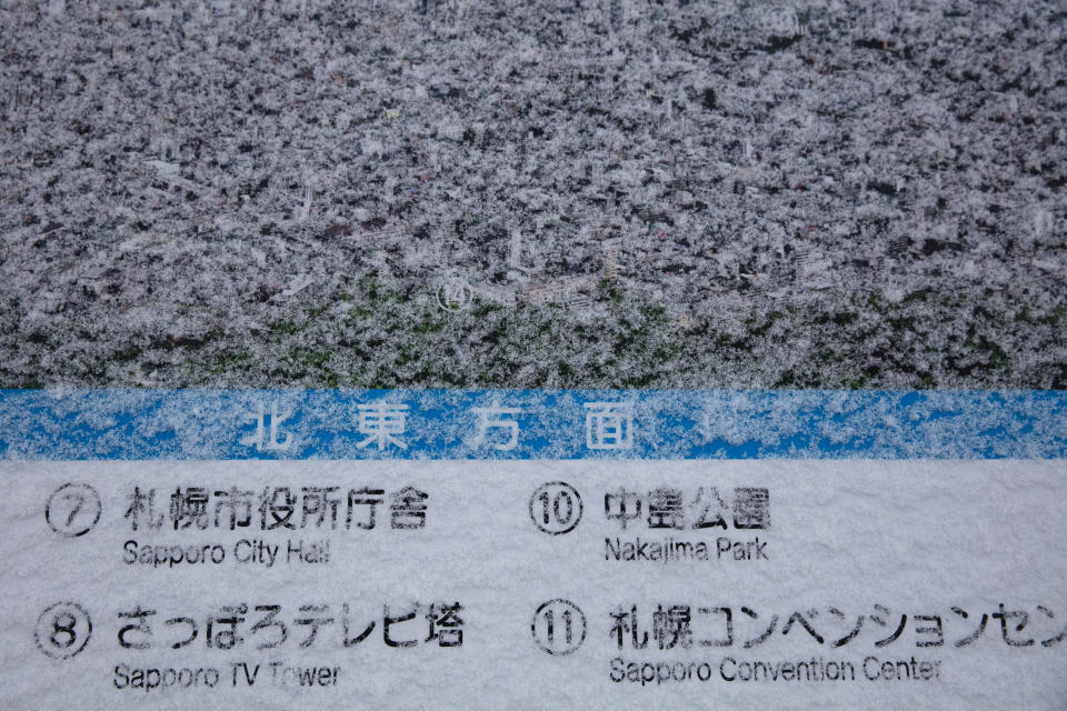 A map showing the city of Sapporo is covered in fresh snow on an observation deck atop Mount Moiwa, Feb. 4, 2020, in Sapporo, Hokkaido, Japan. After two months of almost no snow, Japan's northern city of Sapporo was overwhelmed with the white stuff. (AP Photo/Jae C. Hong)
