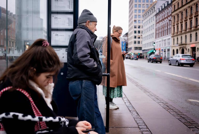 Los viajeros esperan en una parada de autobús en Copenhague el 1 de febrero de 2022, cuando Dinamarca se convierte en el primer país de la UE en levantar las restricciones de coronavirus