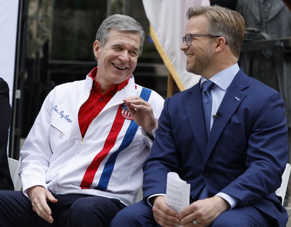 North Carolina Governor Roy Cooper, left, laughs with Speedway Motorsports President and CEO Marcus Smith during a press conference announcing that the NASCAR All-Star Race will be held at North Wilkesboro Speedway in May 2023, on the steps of the N.C. Museum of History in Raleigh, N.C., Thursday, Sept. 8, 2022. (Ethan Hyman/The News & Observer via AP)