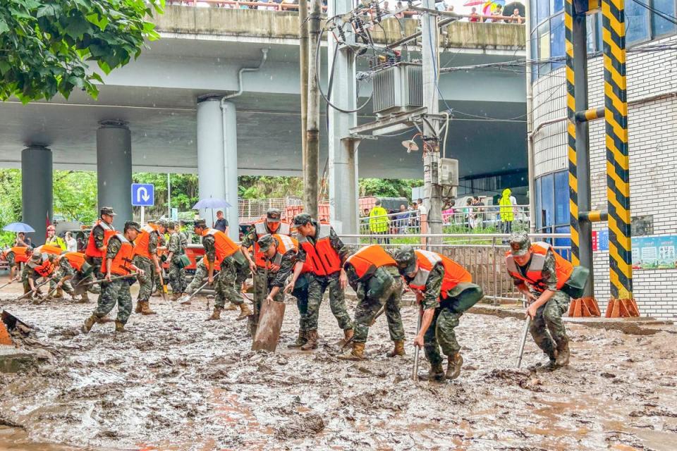 Paramilitary policemen clear a street after flooding caused by heavy rains in China’s southwestern Chongqing (AFP via Getty Images)