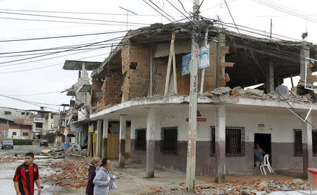 People walk by damaged buildings after an earthquake struck off Ecuador's Pacific coast, at Tarqui neighborhood in Manta April 17, 2016. REUTERS/Guillermo Granja