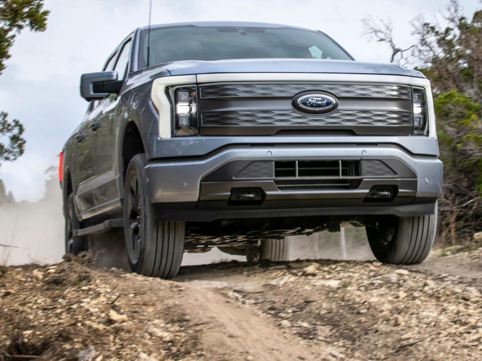 The 2022 Ford F-150 Lightning Lariat driving on a dirt road.