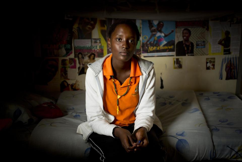 In this photo taken Monday, March 24, 2014, student Sharon Kalisa, 17, whose favorite subject is history and particularly genocide studies, sits in her bedroom at the Agahozo-Shalom Youth Village near Rwamagana, in Rwanda. Most of the kids in a Rwandan school set amid the lush green, rolling hills of eastern Rwanda don’t identify themselves as Hutu or Tutsi. That’s a positive sign for Rwanda, which is now observing the 20th anniversary of its genocide, a three-month killing spree that, according to the official Rwandan count, left more than 1 million people dead, most of them Tutsis killed by Hutus. The teenagers attending the Agahozo-Shalom Youth Village, a school with dorms that creates tight-knit student families, say the ethnic slaughter that their parents or grandparents were a part of either as victims or perpetrators won’t be repeated. The school director echoes the sentiment. (AP Photo/Ben Curtis)