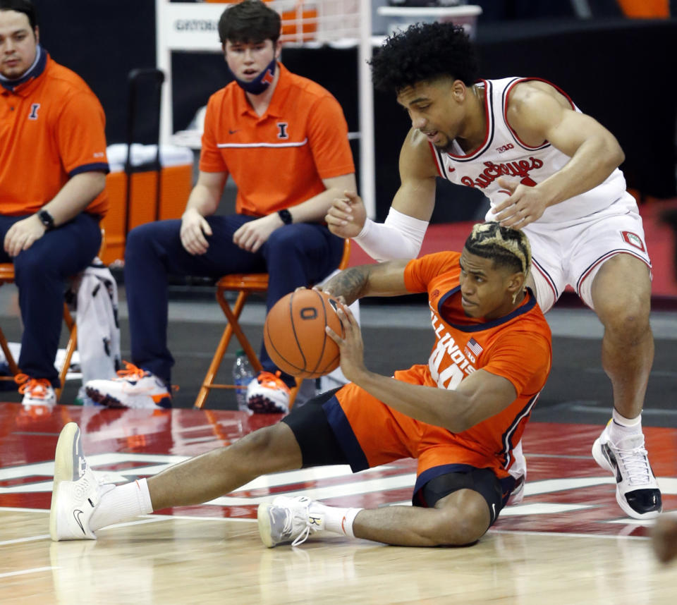 Illinois guard Adam Miller, bottom, passes against Ohio State forward Justice Sueing during the first half of an NCAA college basketball game in Columbus, Ohio, Saturday, March 6, 2021. (AP Photo/Paul Vernon)