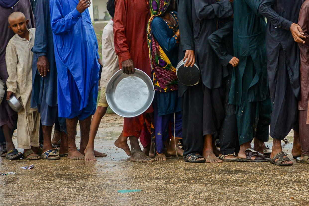 Men and children in Pakistan queue up to receive food near a temporary shelter set at a school in a coastal area in Sujawal, Sindh province (AFP via Getty Images)