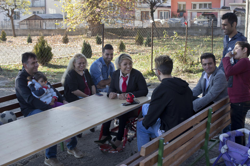 In this photo taken Tuesday, Nov. 13, 2018, Mahana Jami, 34, center, talks to friends inside a government run camp for refugees and migrants in Bosilegrad, some 250 kilometers southeast of Belgrade, Serbia. As a little girl in a wheelchair in Iran, Jami used to watch other children play on a slide and wondered why she couldn't do the same. She then made a promise to herself to always dream big and never let her disability stand in the way. (AP Photo/Marko Drobnjakovic)