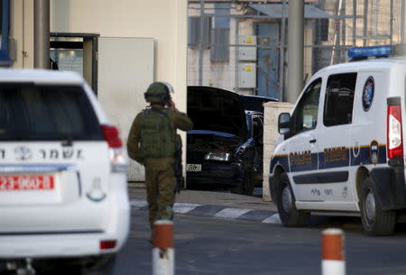 An Israeli soldier stands in front of a car (C) used by a Palestinian man in what an Israeli police spokesman said was a car ramming attack at the Qalandiya checkpoint between Jerusalem and the West Bank, December 18, 2015. REUTERS/Baz Ratner