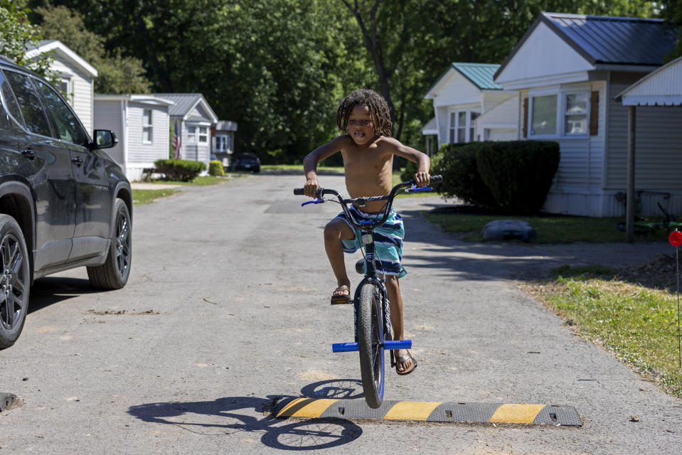 Jahi Black, 7, uses a speed bump as a jump for his bike outside of his grandmother's home in the Ridgeview Homes mobile home community in in Lockport, N.Y., June 23, 2022, Despite 123 mobile homes being occupied in the community, there is no designated play area for kids. (AP Photo/Lauren Petracca)