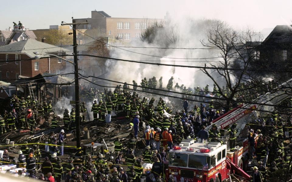 Firefighters look for victims at the smouldering remains of the American Airlines flight 587 in Queens, New York City