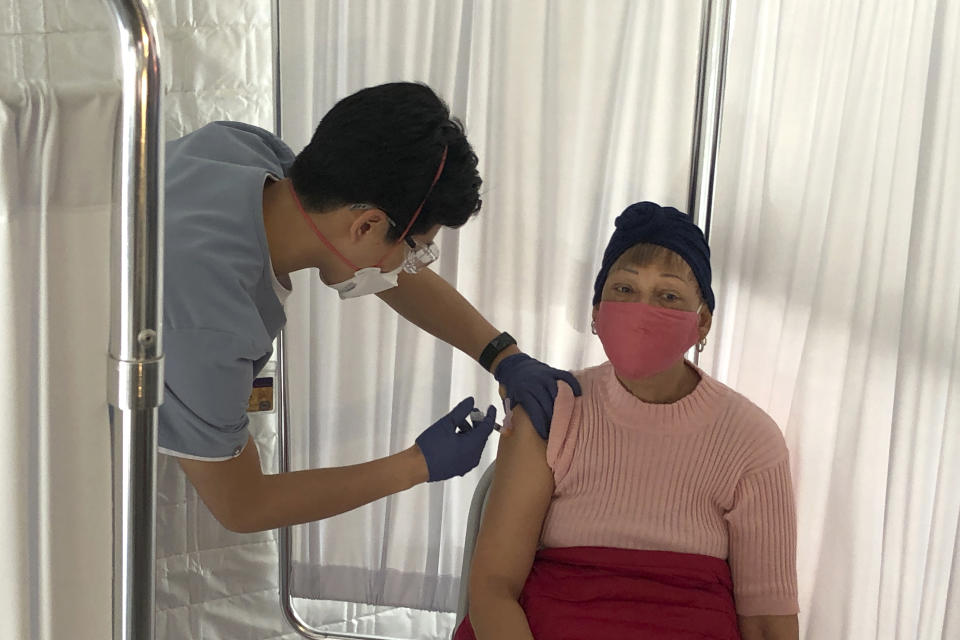 Shelia Auzenne, 68, right, receives a COVID-19 vaccine shot from a health care worker at a vaccination site in the Bayview neighborhood of San Francisco, Monday, Feb. 8, 2021. Counties in California and other places in the U.S. are trying to ensure they vaccinate people in largely Black, Latino and working-class communities that have borne the brunt of the coronavirus pandemic. San Francisco is reserving some vaccines for seniors in the two ZIP codes hit hardest by the pandemic. (AP Photo/Haven Daley)