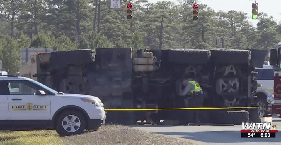 In this image taken from video, authorities work at the scene of a fatal crash after a military truck overturned, Wednesday, Jan. 19, 2022, near Camp Lejeune, N.C. Two U.S. Marines were killed and 17 others were injured when the truck they were riding in overturned Wednesday and ejected them near their base in North Carolina, authorities said. (WITN via AP)