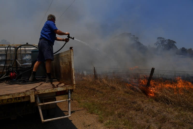 Tinonee resident Brian Acheson sets up his tip truck as a makeshift fire truck to assist residents fighting spot and grass fires in the Hillville area near Taree