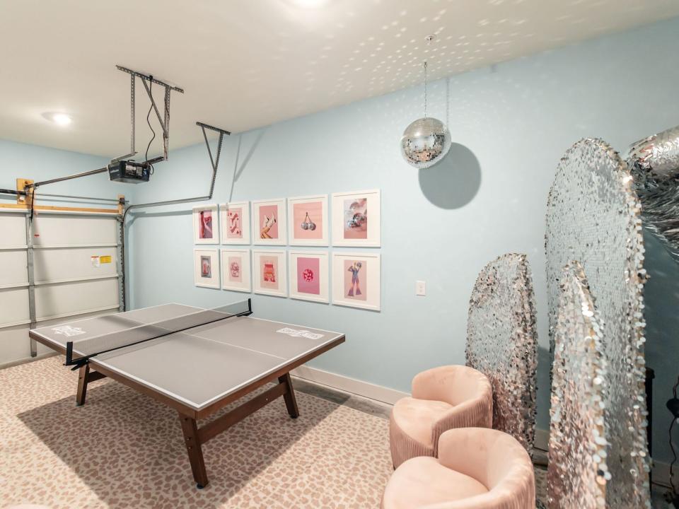 A garage with prints, a ping pong table, and a disco ball.