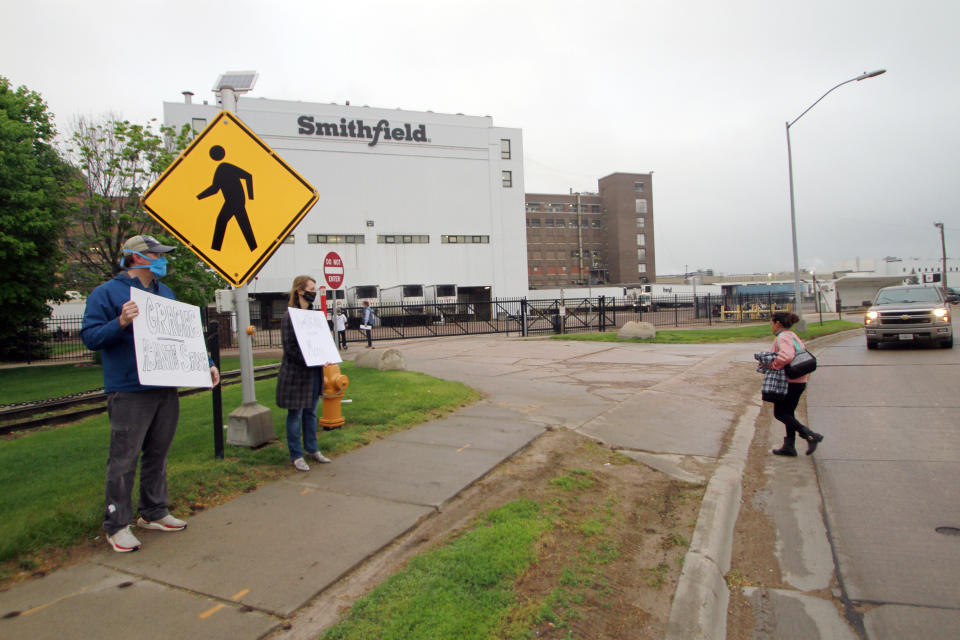 FILE - In this May 20, 2020, file photo, residents cheer and hold thank-you signs to greet employees of a Smithfield pork processing plant as they begin their shift in Sioux Falls, S.D. Workers on farms and at meatpacking plants who were severely affected by the coronavirus pandemic will be eligible to get grants of up to $600 per person as part of a new $700 million aid program the U.S. Department of Agriculture announced Tuesday, Sept. 7, 2021. (AP Photo/Stephen Groves, File)