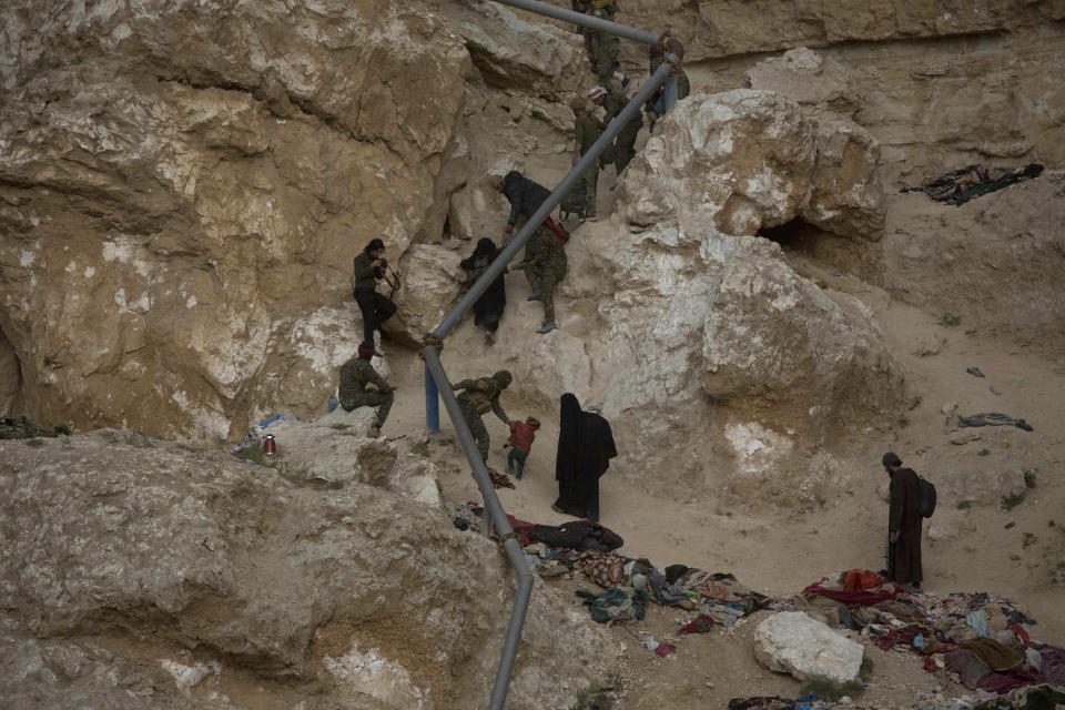 People who left the besieged Islamic State-held village of Baghouz, Syria, scramble up a rocky hillside to be checked by U.S-backed Syrian Democratic Forces Thursday, March 14, 2019. (AP Photo/Maya Alleruzzo)
