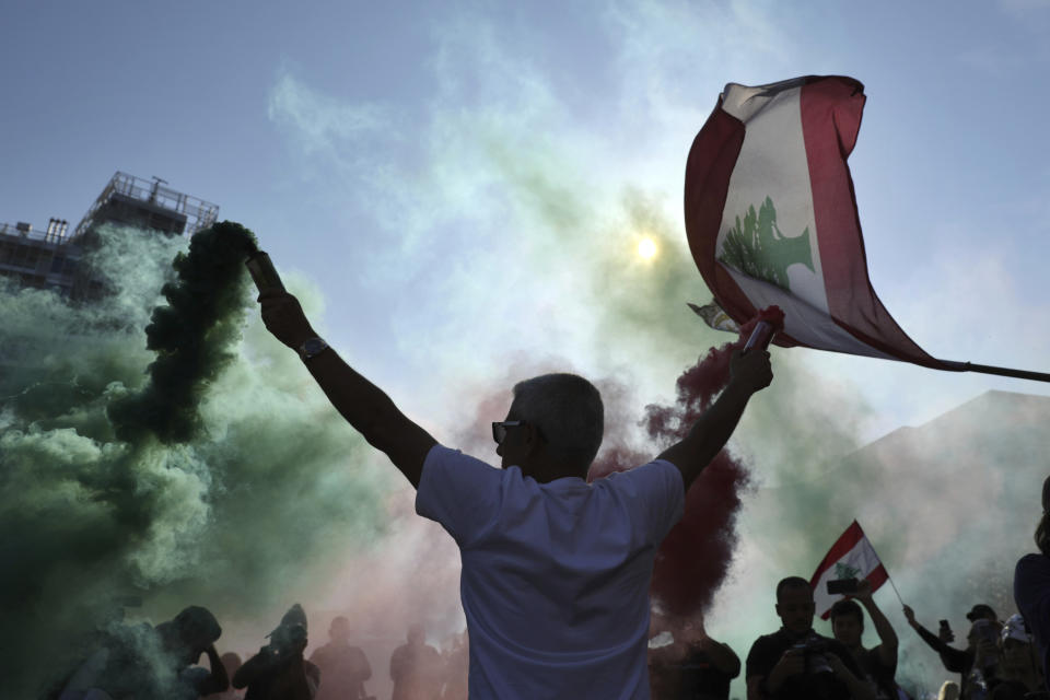 Anti-government protesters wave Lebanese national flags as they gather during a separate civil parade at the Martyr square, in downtown Beirut, Lebanon, Friday, Nov. 22, 2019. Protesters gathered for alternative independence celebrations, converging by early afternoon on Martyrs’ Square in central Beirut, which used to be the traditional location of the official parade. Protesters have occupied the area, closing it off to traffic since mid-October (AP Photo/Hassan Ammar)