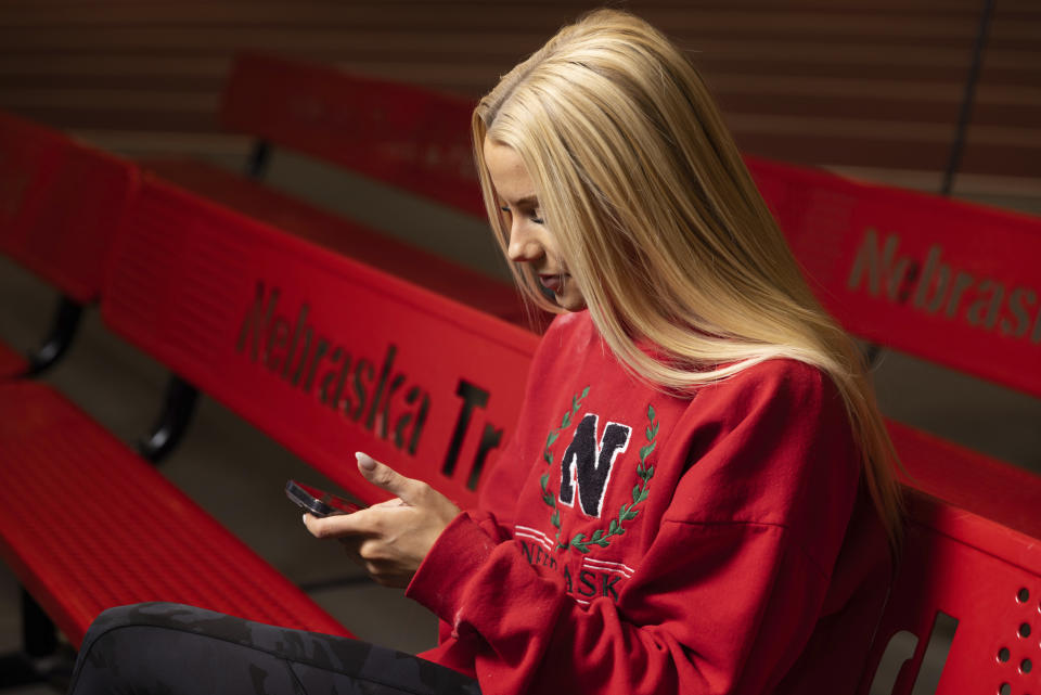 Nebraska NCAA college pole vaulter Jessica Gardner looks at her phone Thursday, March 9, 2023, in Lincoln, Neb. Gardner said she started making TikToks last year with her roommate and they were surprised at how many views they generated. With college athletes now able to cash in on their celebrity, Gardner began looking for ways to monetize them and now partners with about 15 brands, most of them catering to women. (AP Photo/Rebecca S. Gratz)