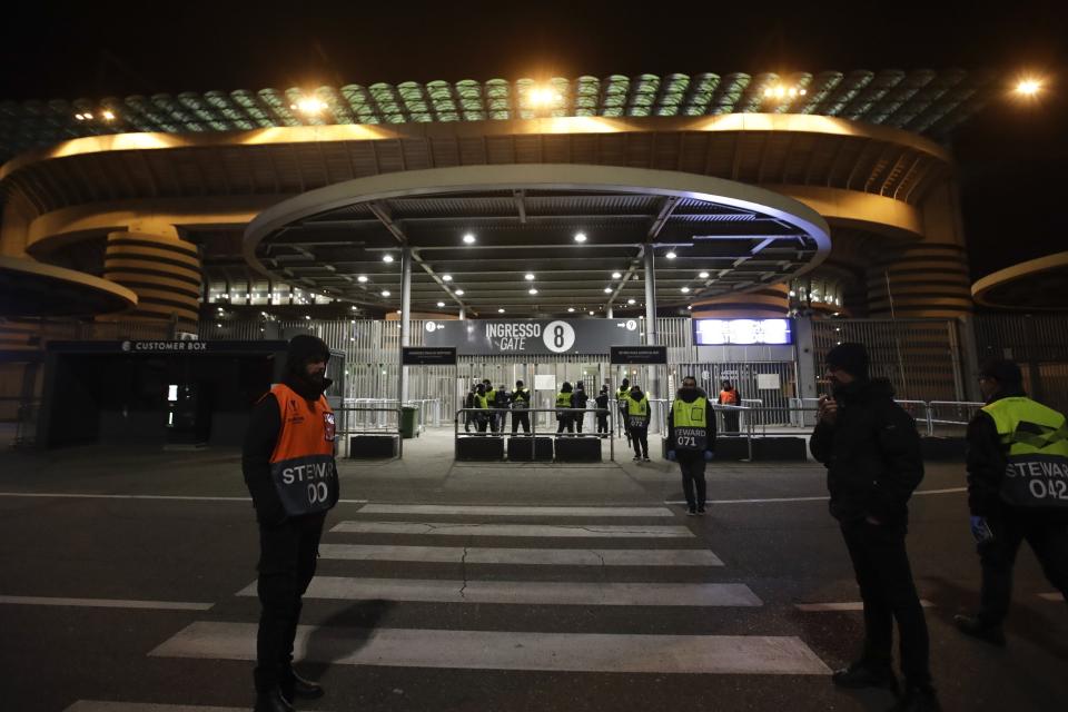 Stewards stand at a gate of the San Siro stadium in Milan, Italy, Thursday, Feb. 27, 2020. Ludogorets is playing Italian club Inter Milan in a Europa League soccer match on Thursday that is scheduled to go ahead in an empty stadium due to the coronavirus outbreak. (AP Photo/Luca Bruno)