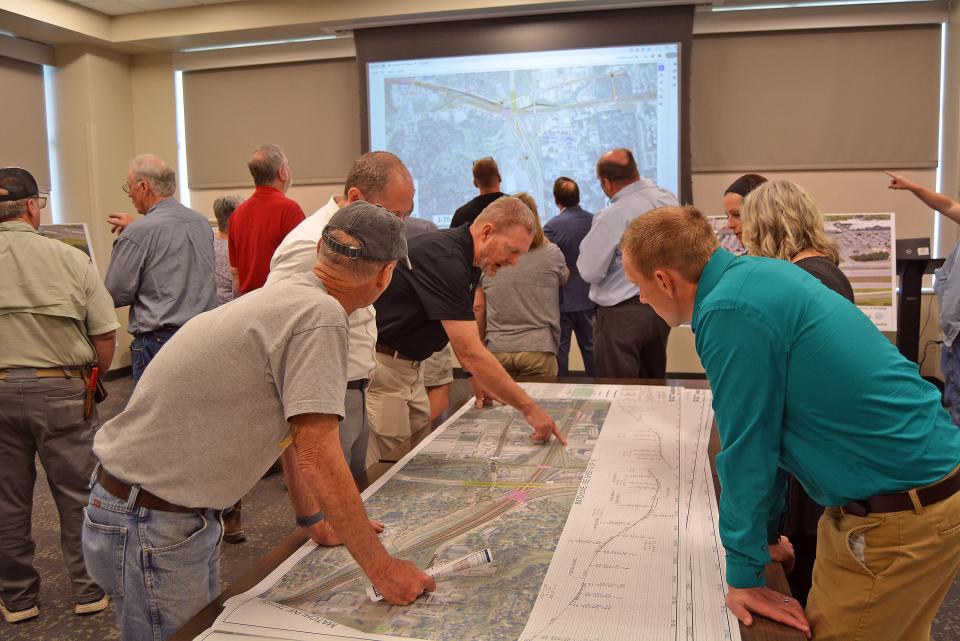 Bob Leingang, center leaning over in black shirt, executive vice president and chief engineer with Millstone Weber, points to a section of plans Wednesday focused on the Interstate 70, U.S. Highway 63 connector to answer questions from area residents.