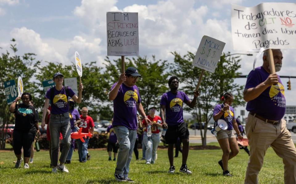 Airport service workers hold up picket signs during a rally near the intersection of Wilkinson Boulevard and Josh Birmingham Parkway.