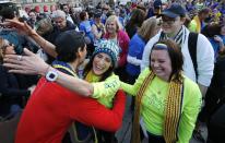 Boston Marathon bombing survivors Doug Julian, left, and his partner Lynn Crisci, center, hug as fellow survivor Shannon Silvestri, right, looks on in Boston, Sunday, April 13, 2014. The trio, joined by other survivors, family members and supporters met up with participants of a cross country charity relay that began in March in California and ended Sunday at the finish line of the Boston Marathon. (AP Photo/Michael Dwyer)