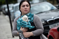 <p>A woman carries a dog from the Dorney Tower residential block, as residents were evacuated as a precautionary measure following concerns over the type of cladding used on the outside of the buildings on the Chalcots Estate in north London, Britain, June 25, 2017. (Photo: Hannah McKay/Reuters) </p>