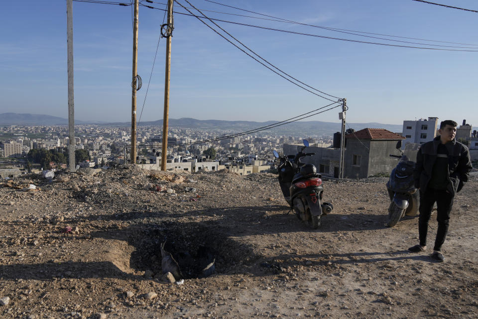 Palestinians inspect the site where a roadside bomb killed one Israeli paramilitary police officer and injured three others during overnight clashes in the Jenin refugee camp, West Bank, on Sunday, Jan. 7, 2024. Six Palestinians and a member of Israel's paramilitary border police were killed in confrontations in a hot spot of violence in the Israeli-occupied West Bank, the Palestinian Health Ministry and the Israeli military said Sunday. (AP Photo/Majdi Mohammed)