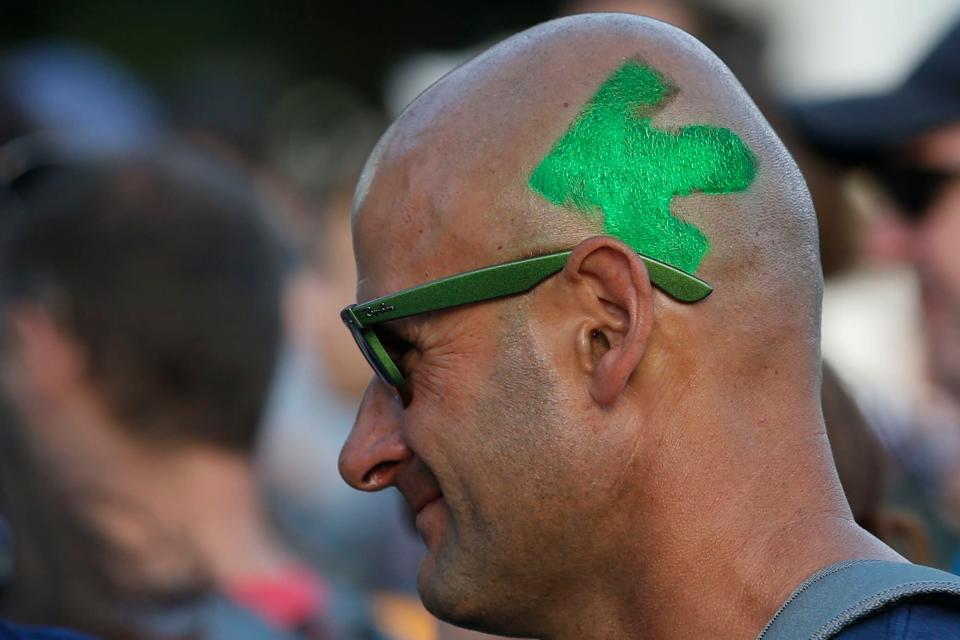 A man walks through the crowd sporting a painted Pelotonia logo on the side of his head during Pelotonia 2017's opening ceremonies.