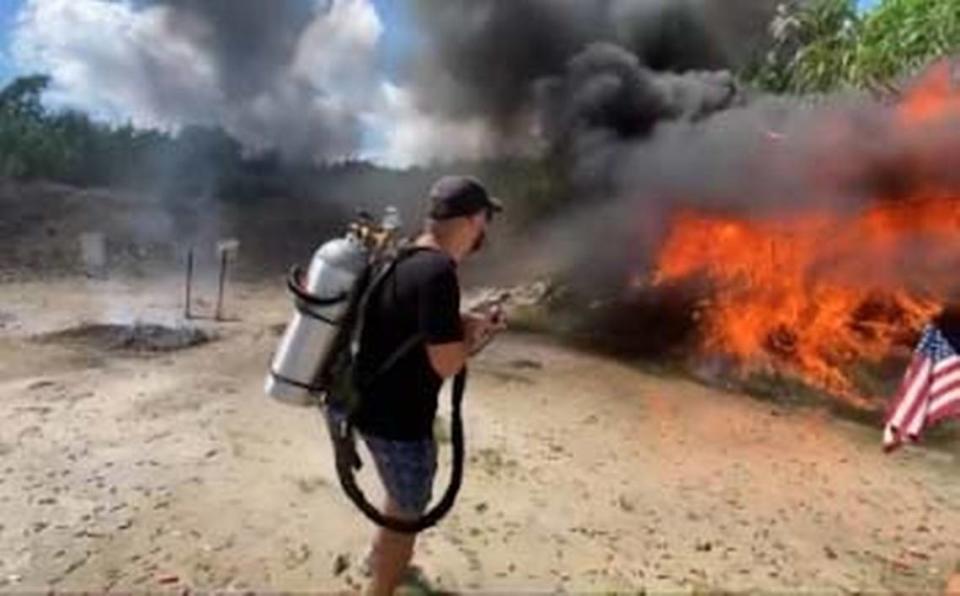 In a photo posted on social media, a man with a flamethrower scorches the foliage at Henry’s Sport Shooting Range.