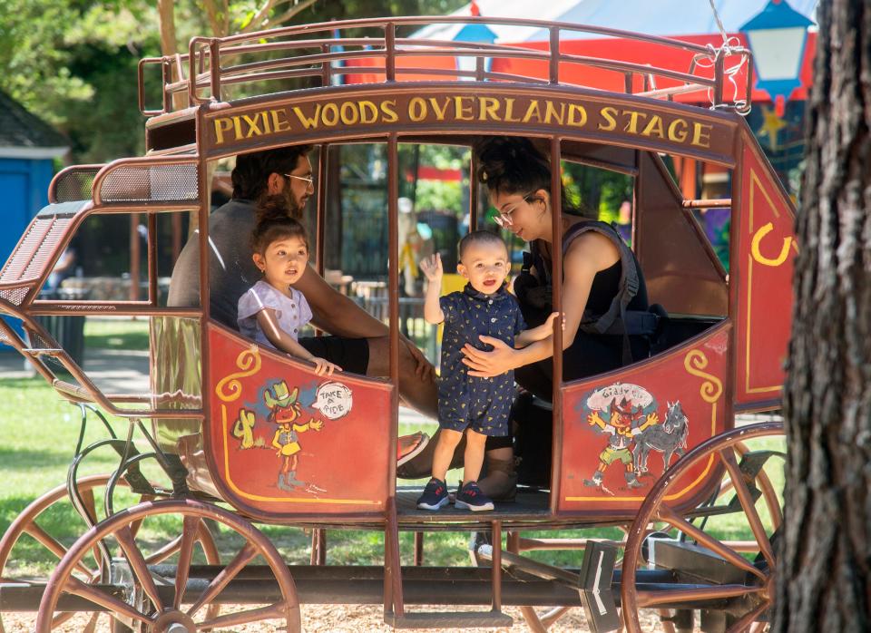 Beto Garcia, left rear, Daisy Muñoz of Oakdale, and their children Bellis Garcia, 7, left, and Benjamin Garcia, 1, sit in the stage coach on opening day at Pixie Woods.