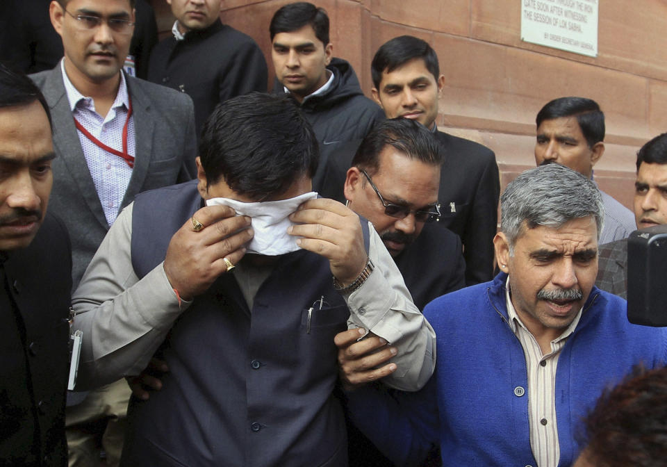 An unidentified member of India's parliament covers his face with a handkerchief after being affected by pepper spray gas in New Delhi, India, Thursday, Feb. 13, 2014. Congress party lawmaker L. Rajagopal from Andhra Pradesh sprayed pepper spray inside the parliament from the main speaking zone, creating chaos that left his colleagues coughing and crying as they were ushered from the hall, in a protest over a long-contentious proposal to create a new southern state of Telangana from the existing Andhra Pradesh state. (AP Photo)