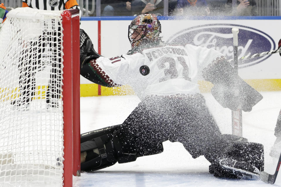 The puck passes behind Arizona Coyotes goaltender Scott Wedgewood (31) during the second period of the team's NHL hockey game against the New York Islanders, Friday, Jan. 21, 2022, in Elmont, N.Y. (AP Photo/Corey Sipkin).