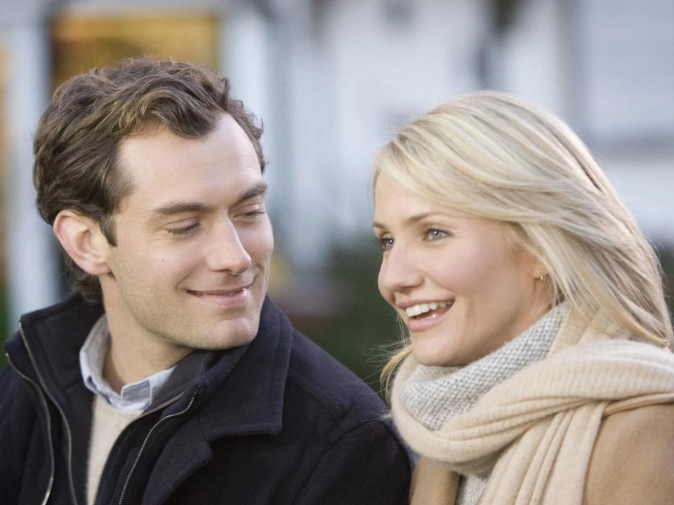 Jude Law in a black jacket looking at Cameron Diaz in a cream jacket and scarf