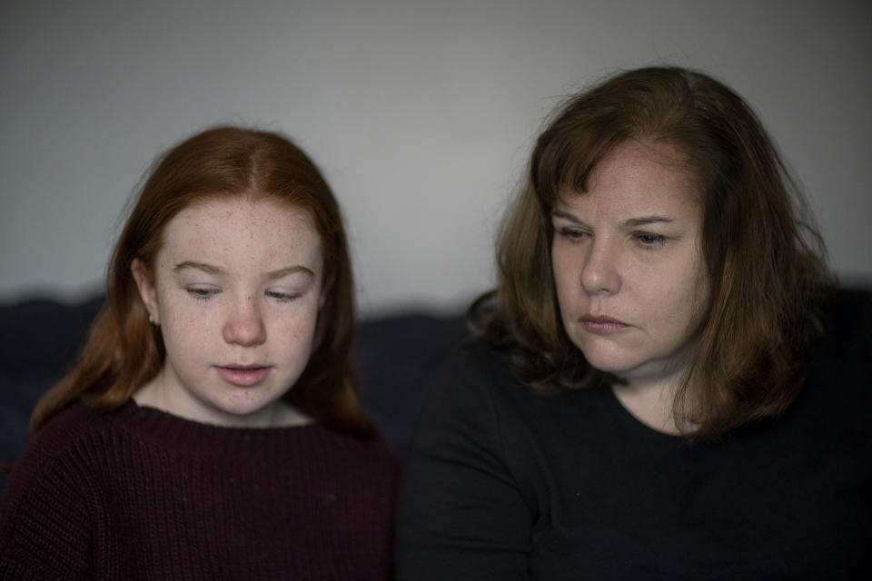 Eileen Carroll, right, sits with her daughter, Lily, 11, as she attends school remotely from their home in Warwick, R.I, Wednesday, Dec. 16, 2020. When Carroll's other daughter tested positive for the coronavirus, state health officials told her to notify anyone her daughter might have been around. Contact tracers, she was told, were simply too overwhelmed to do it. It's the same story across the U.S., as a catastrophic surge in infections has made it difficult or impossible to keep up with the calls considered critical to controlling outbreaks. (AP Photo/David Goldman)