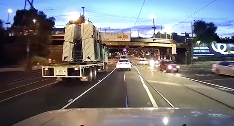 Dash cam photo of car travelling behind a truck before it slams into an overpass. 